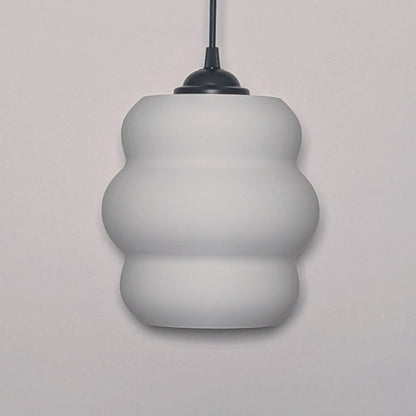 The Mammatus Pendant Light by Dryft Home features a modern, three-tiered bulbous design crafted from sustainable material. Its white form, suspended from a black cord, adds an eco-friendly touch that complements any decor.