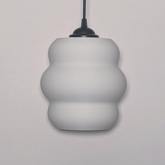 The Mammatus Pendant Light by Dryft Home features a modern, three-tiered bulbous design crafted from sustainable material. Its white form, suspended from a black cord, adds an eco-friendly touch that complements any decor.
