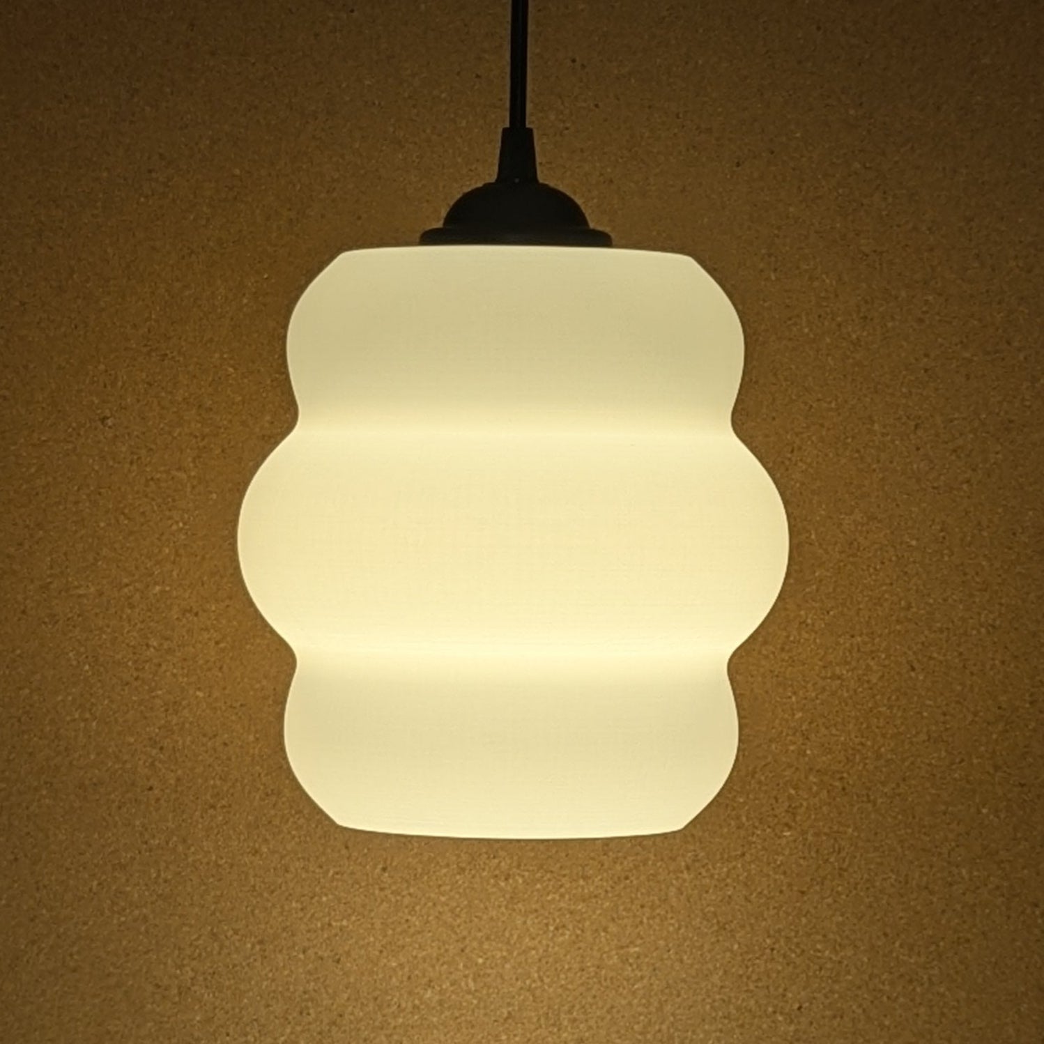 Against a beige background, the Mammatus Pendant Light by Dryft Home glows with its wavy, white fabric texture. Crafted from sustainable materials, it offers an elegant and modern touch to any room.