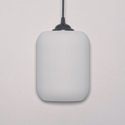 The Cumulis Pendant Light by Dryft Home showcases a modern design with a cylindrical textured white shade made from sustainable materials and a sleek black fixture, elegantly set against a plain white background.