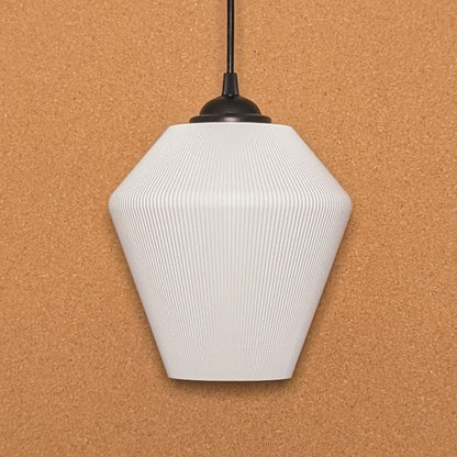 The Inversis Pendant Light by Dryft Home is made from sustainable materials, showcasing a white geometric form with a ribbed texture. It hangs elegantly from a black cord against a cork backdrop, featuring an angular polygonal design that brings modern elegance to any room.