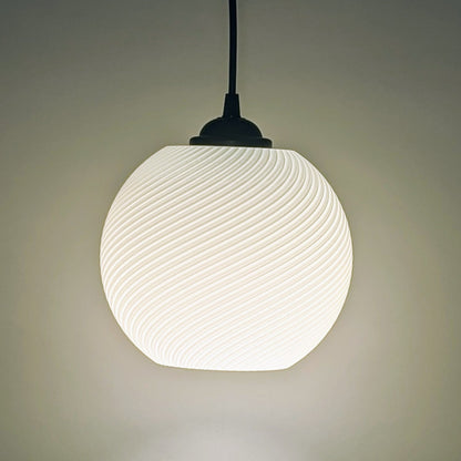 The Vortice Pendant Light by Dryft Home features a 3D printed, swirling pattern. Crafted from biodegradable PLA plastic, it emits a soft glow and hangs from a dark cord, exemplifying modern, sustainable lighting against a neutral background.