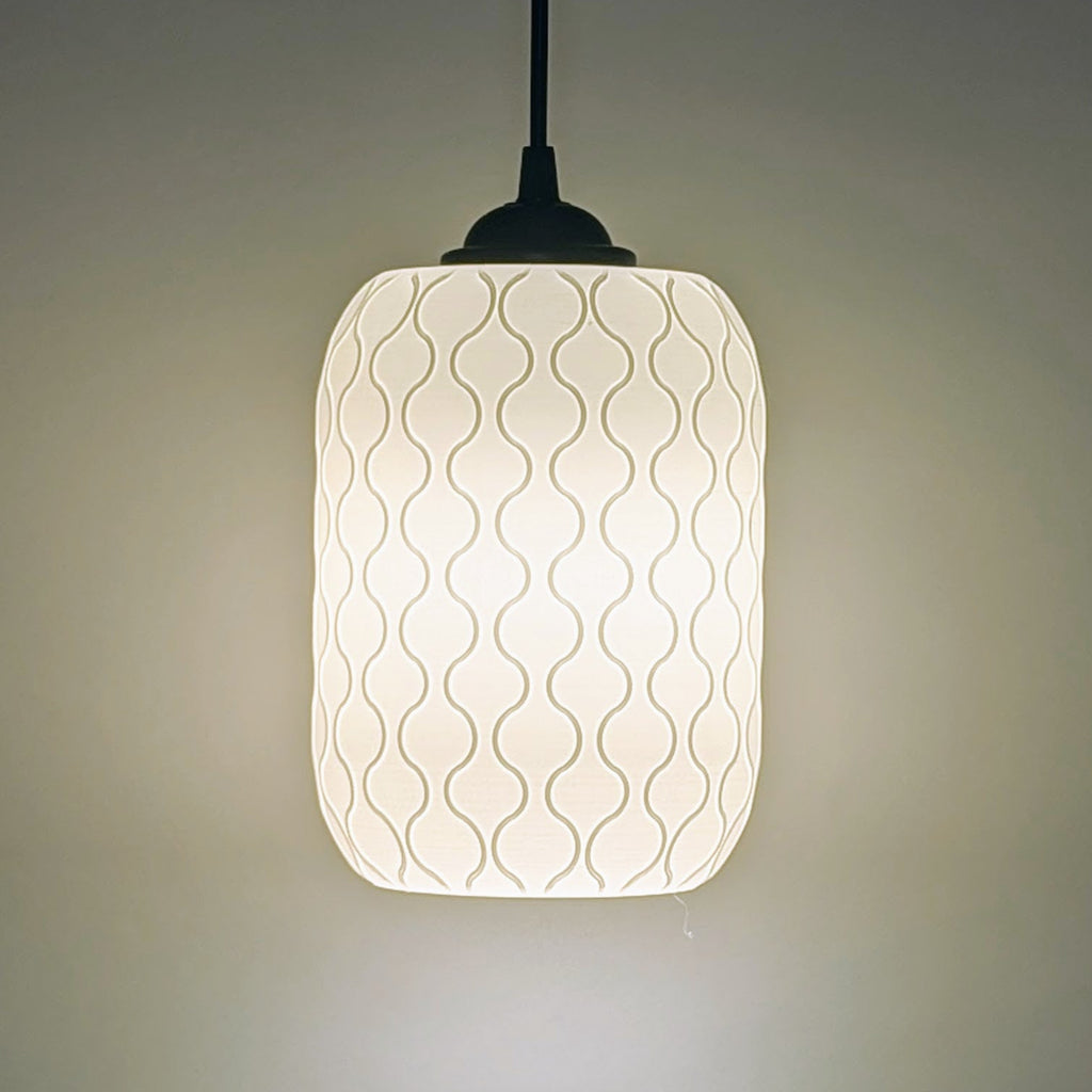 The Cirrus Pendant Light by Dryft Home features a white cylindrical shade made from sustainable materials with a subtle wavy line pattern, casting a warm glow against a plain background.